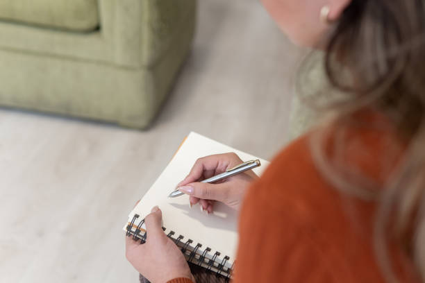 istock close-up of a woman's hand from behind making note in a notebook 1988528192