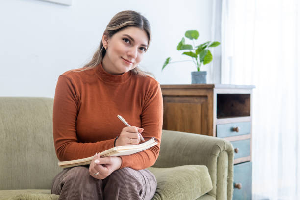 Young female psychologist looking at camera with her notebook and a pen