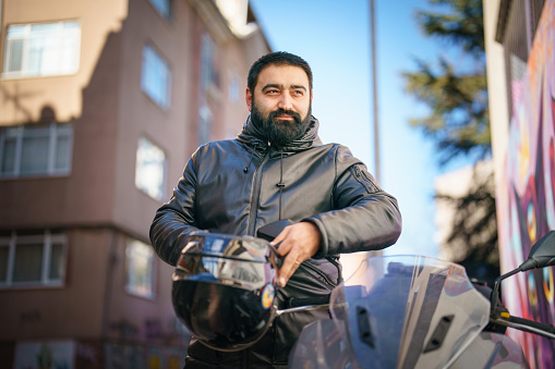 Biker with beard and tough look sitting on a motorcycle looking at camera with a menacing stare. Image shot with, Canon 5D Mark2, 100 ISO, 24-115mm lens