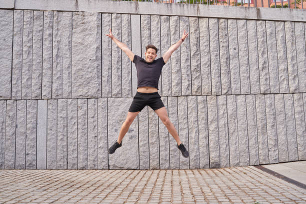 istock young enthusiastic latin man jumping with arms and legs wide open 1988576467