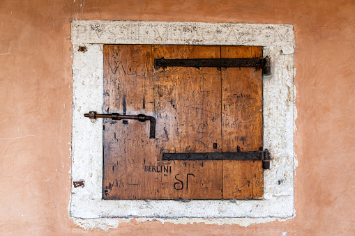 Roma, Latium - Italy - 11-25-2022: Weathered wooden door with traditional iron lock and latch, symbolizing old-world craftsmanship, with letters and words engraved and the word berlini