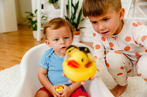 Siblings playing with rubber duck in the living room