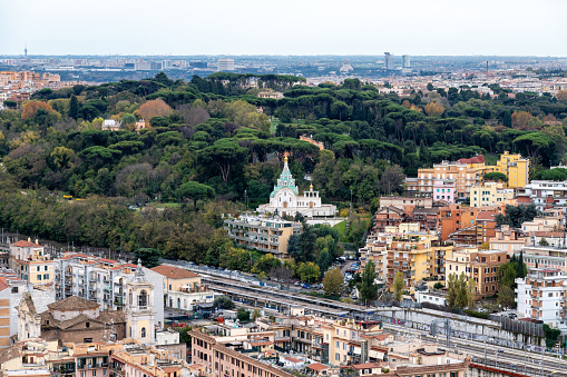 Roma, Latium - Italy - 11-26-2022: Lush greenery contrasts with urban structures in Rome, framing a serene cityscape against a bustling background, showing the church Santa Caterina Martire
