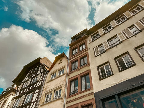 Looking up at historical European style architecture in the city square of Strasbourg, France. Half-timbered style architecture. Peaked roofs reach towards a cloudy Summer sky.