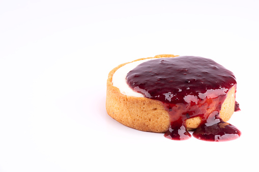 cheese cake with spilling dripping berry jam isolated on white background at angle in corner