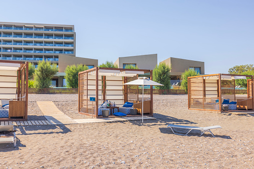 Rhodes. Greece. 07.25.2023. Row of wooden covered shelters on the beach on a bright sunny day.