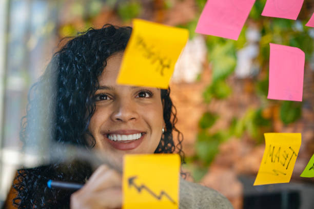 istock Business woman writing on sticky notes on window. 1988645986