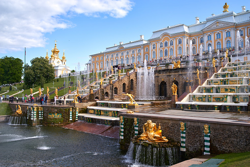 St Petersburg, Russia - August 27, 2017:  Samson Fountain at Peterhof commands attention with its grandeur and symbolism, featuring a towering statue of Samson triumphantly wrestling a lion, while water gushes forth in a dramatic display, embodying strength and victory.\n\nPeterhof, or the Peterhof Grand Palace, is a magnificent palace complex located in Peterhof, in the outskirts of Saint Petersburg, Russia. Commissioned by Peter the Great in the early 18th century with stunning gardens and intricate architecture.\n\nThe grand centerpiece of the Grand Cascade, the sculptural group \