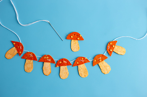 a string of orange mushrooms made of dried tangerine peel on a blue background, conceptual art, flat lay