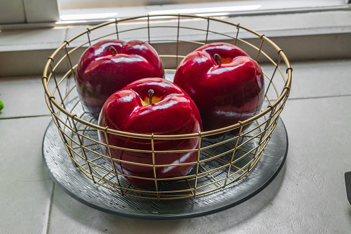 Red vivid plastic apples on a  metal basket