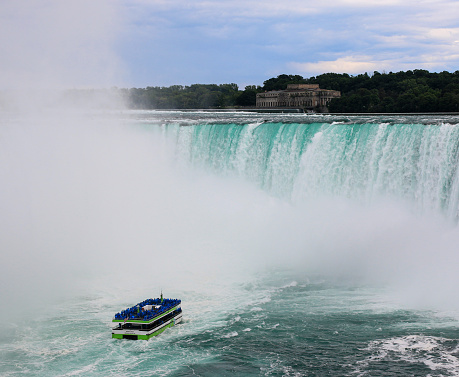 Niagara Falls, Onterio, Canada - 30 July 2023: Niagara Falls tour boat with tourists in blue raincoats approaching the mist of Horseshoe Falls.