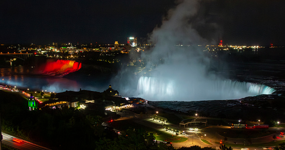 Looking down at Niagara Falls lit up in colors at night from a hotel room.