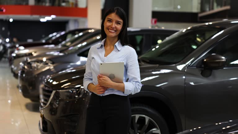 Video portrait of a happy car saleswoman smiling while facing the camera and holding a digital tablet