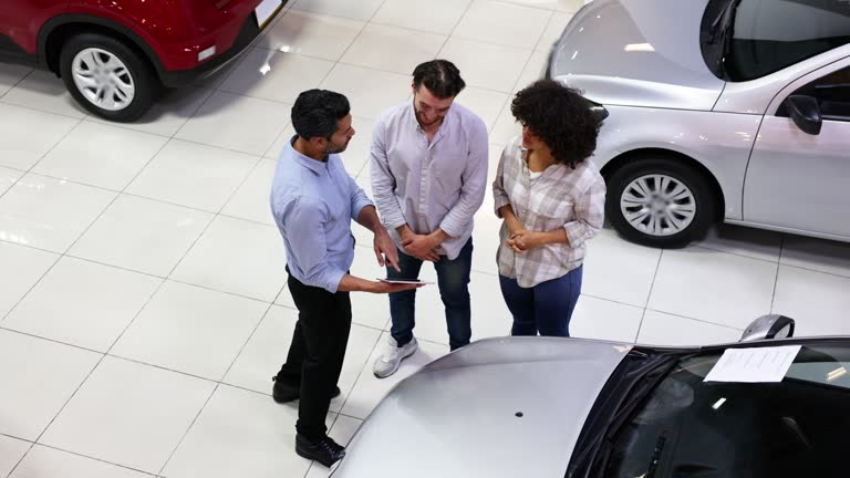 Latin American salesman showing a car to a couple at the dealership