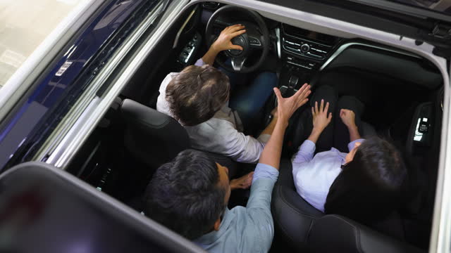 Salesman at the dealership showing a car with sun roof to a couple interested in buying it