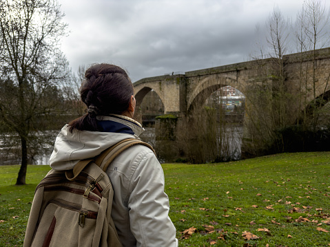 Contemplative Solo Traveler Gazing at Historic Bridge