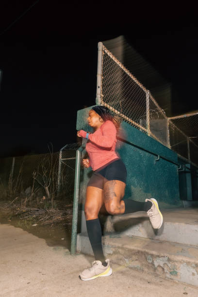 black woman mid-air while running in los angeles at night - city night lighting equipment mid air imagens e fotografias de stock