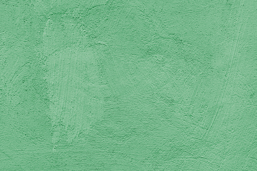 Old stucco plaster surface, brushstroke background, close up grunge texture of green painted cement, concrete wall texture. Wallpaper, backdrop, architecture design element