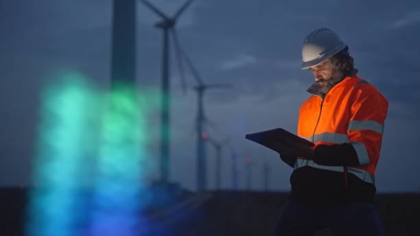 istock Engineer works with HUD holographic in wind farm. Night shift. 1988797797