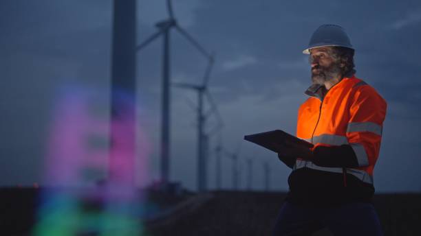 istock Engineer works with HUD holographic in wind farm. Night shift. 1988798312