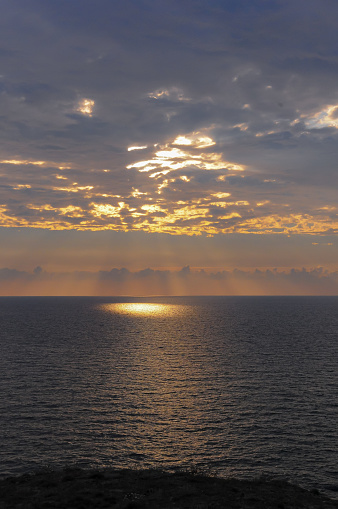 Colorful orange sunrise over the sea, sunbeams in the clouds