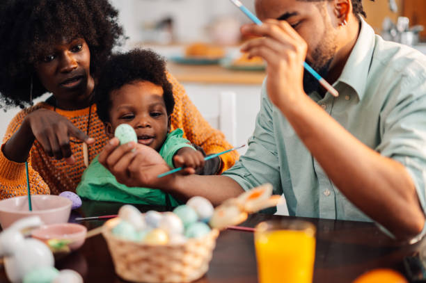 istock Multicultural parents painting easter eggs with their child. 1988812104