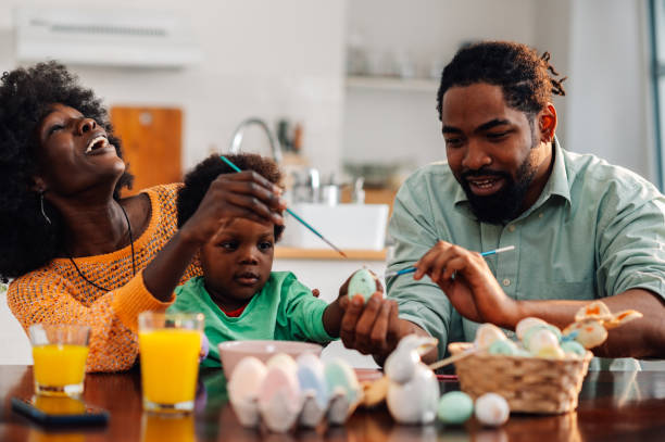 istock Boy toddler is holding easter egg while mother and father paint on it 1988812681