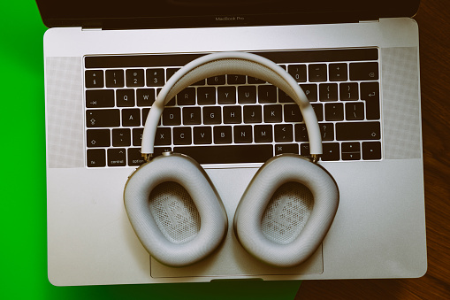 Paris, France - Jan 7, 2020: Directly above view of New best Apple Computers AirPods Max over-ear headphones placed on the keyboard of MacBook pro M1 laptop