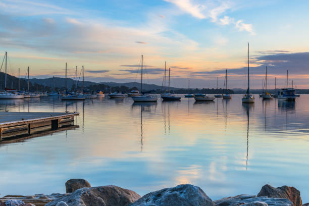 Sunrise reflections with boats on Brisbane Water at Koolewong on the Central Coast, NSW, Australia.