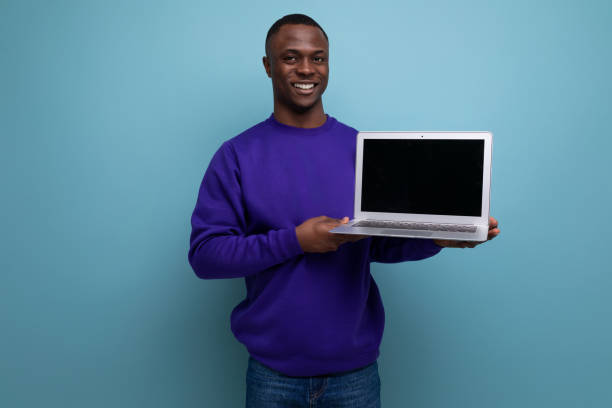 istock 30s dark-skinned American man dressed in a blue sweater shows a screen with a mock-up 1988829380