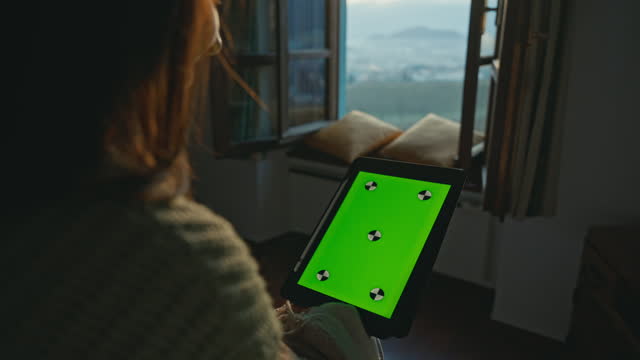SLO MO Over The Shoulder View of Woman Using Digital Tablet with Green Screen Chroma Key near Open Window in Apartment
