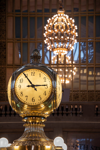 In Manhattan, “meet me at the clock” needs no further explanation - it means the four-sided clock atop the information booth in the main concourse at Grand Central Terminal. 

The clock faces are 24 inches in diameter and covered with opal glass. The acorn at the top is a reference to the Vanderbilt family - Cornelius Vanderbilt owned the New York Central Railroad, which later built Grand Central Terminal. The acorn symbolizes the motto of the Vanderbilt family - “from a little acorn a mighty oak shall grow.” 

In the background is one of the many large, ornate chandeliers that illuminate Grand Central.