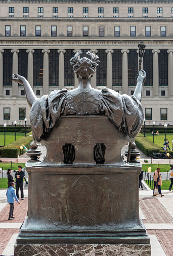 Here is a view of the “Alma Mater” statue at Columbia University, seen from the back. The statue looks south across the quadrangle to the Butler Library. 

The statue’s sculptor was Daniel Chester French (1850-1931,) who, among other famous works, designed the Lincoln statue at the Lincoln Memorial in Washington DC. 

Alma Mater, a representation of the University, wears a crown of laurel leaves and an academic gown. She holds a scepter in her right hand.