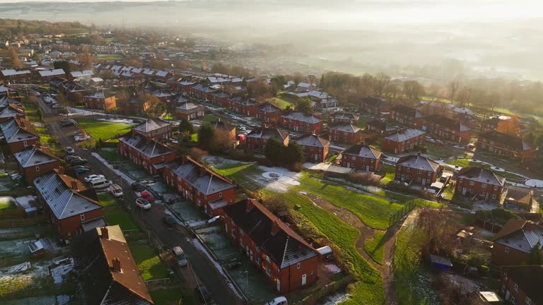 Red brick terraced council community houses in the UK. Bathed in winter sunlight on a cold mist winters day in January, Sunset aerial footage of an urban industrial town in Yorkshire England