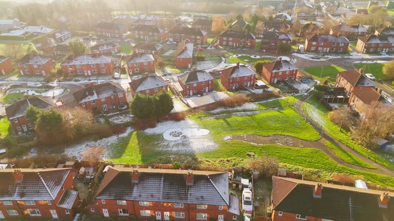Red brick terraced council community houses in the UK. Bathed in winter sunlight on a cold mist winters day in January, Sunset aerial footage of an urban industrial town in Yorkshire England