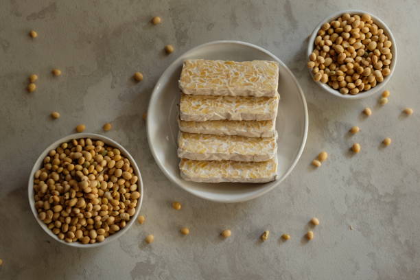 istock Raw tempeh or tempe. tempeh slices in white ceramic bowls and on a marble table. raw soybean seeds in a white ceramic bowl. Tempe is a traditional Indonesian food made from fermented soybeans. 1988922506