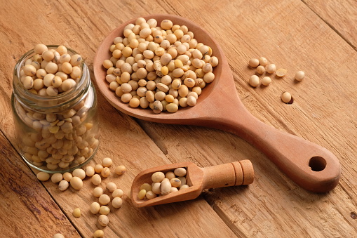 soybeans in a glass jar, on a wooden spoon, on a wooden table