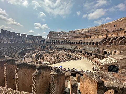 Wide shot of the exposed multiple levels of Rome's Colosseum, with scattered tourists
