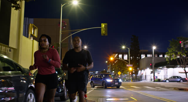 African American Couple Running ahead of Friends at Night in Los Angeles