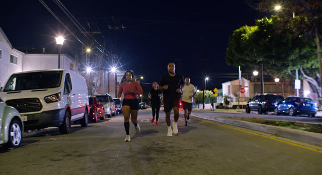 Wide Tracking Shot of African American Couple Running on Street with Friends at Night in Los Angeles