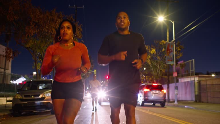 African American Couple Running on Street with Friends Following behind at Night in Los Angeles