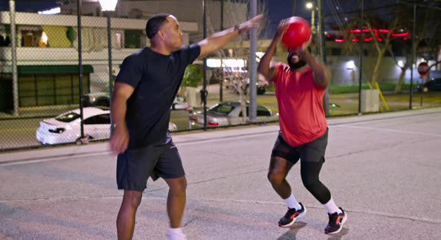 Two Men Playing Basketball at Night in Los Angeles