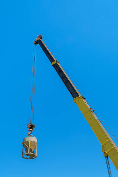 At construction site, tower crane is lifting concrete bucket to pour concrete cement mix into formwork