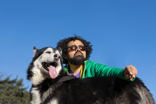 Mexican man with curly hair, with his husky dog, posing in profile