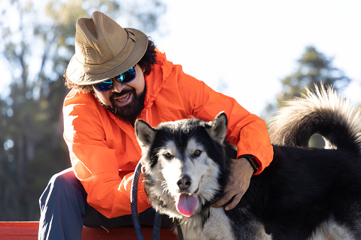 Man wearing a hat and sunglasses with his husky dog in a park in Mexico City