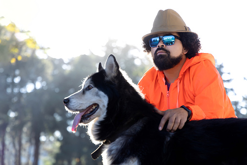 Close-up shot of Mexican man posing with husky dog