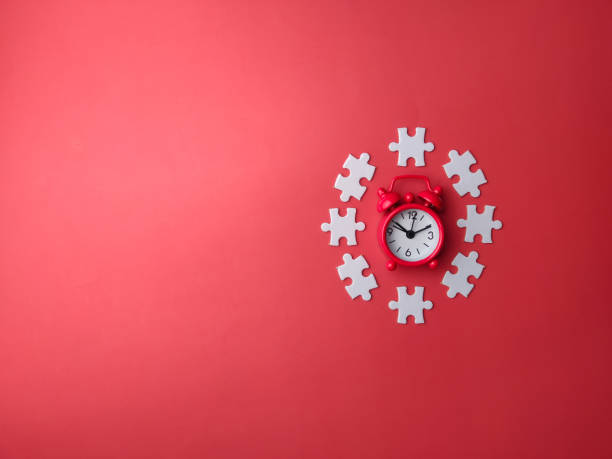 istock Top view red alarm clock with white puzzle on a red background 1989091365