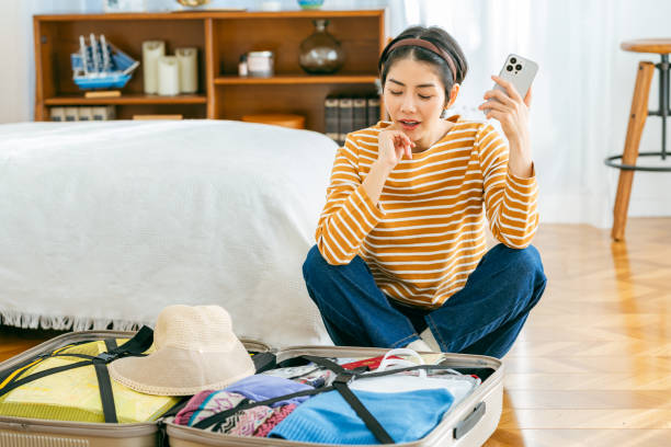 istock Young Japanese woman making reservations online while preparing for a trip 1989135701