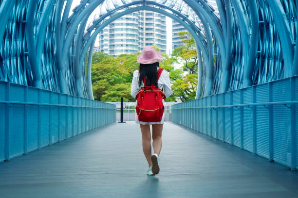 istock Young woman with backpack walking in pedestrian walkway tunnel 1989170802