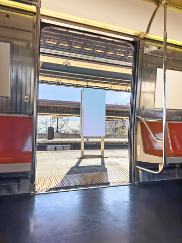 Empty train seats and open doors at a stop on a sunny day